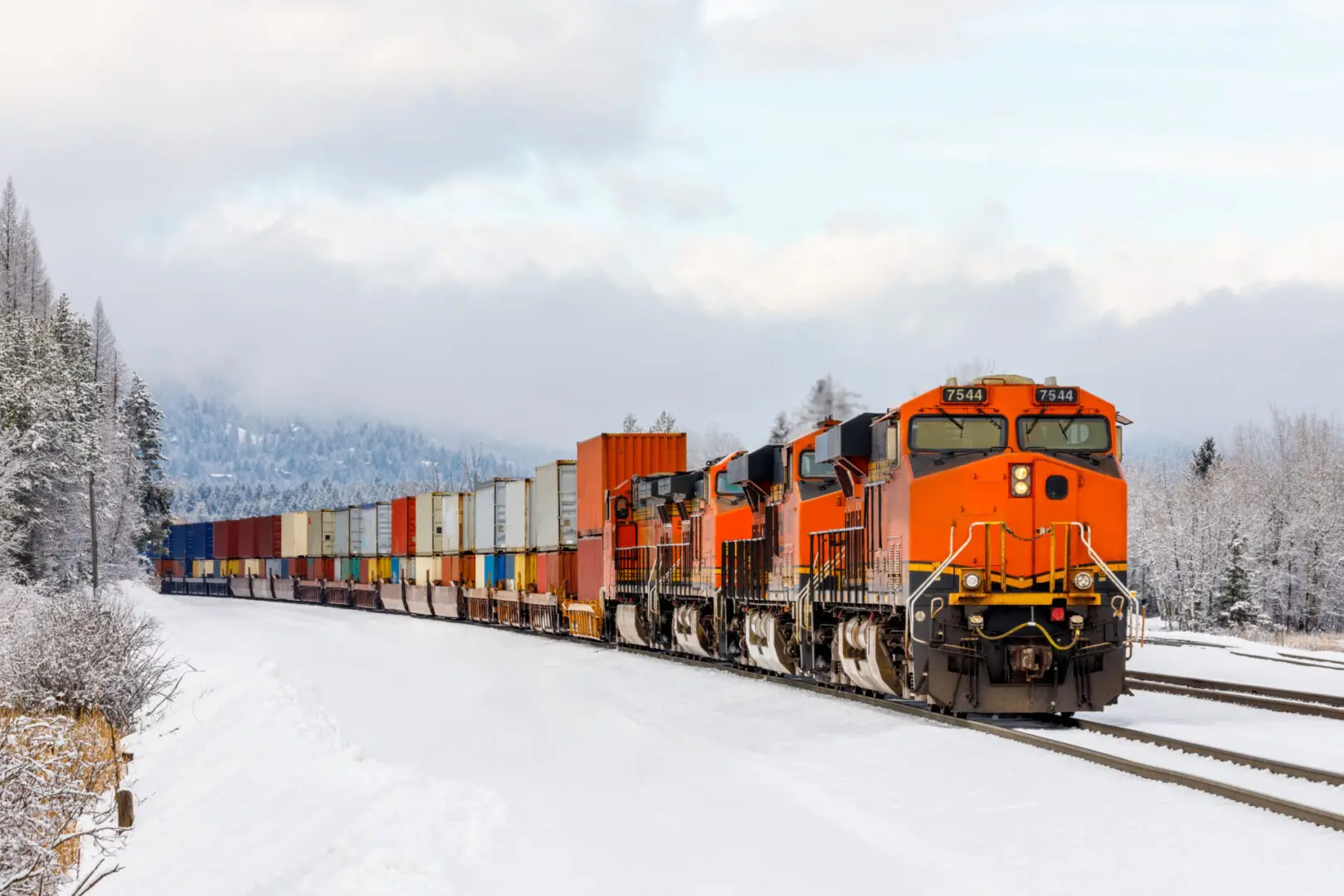 Winter scene of a locomotive pulling a freight train close to Whitefish, Montana with exhaust poring out of the engine on a cold day in January